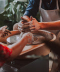 Two people working on a pottery wheel with a blurred background